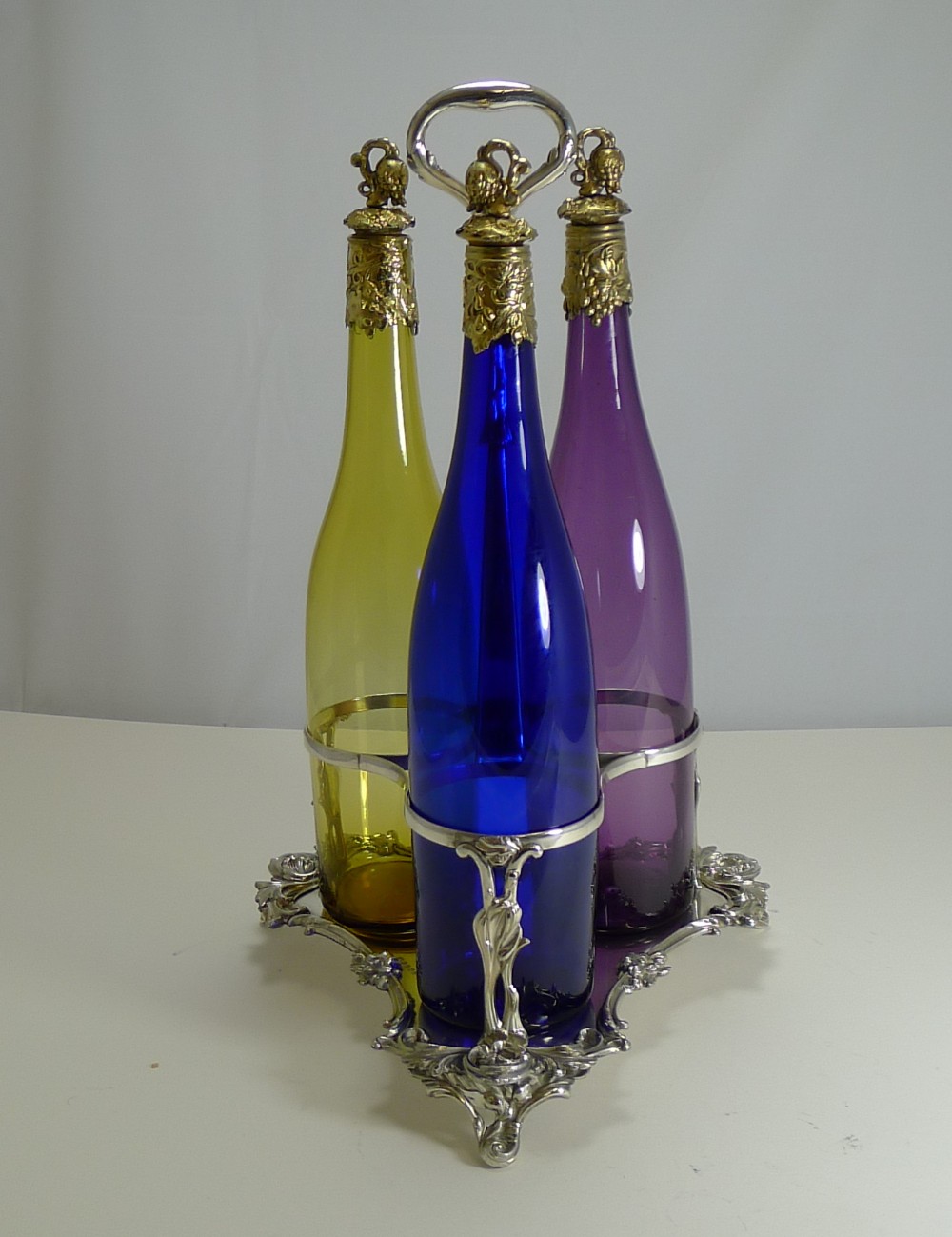 three victorian coloured glass decanters in stand c1890